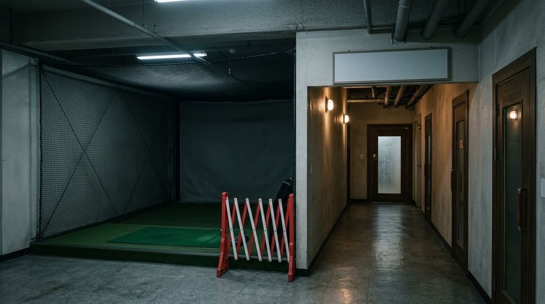 An empty screen golf practice bay closed off inside a complex basement facility