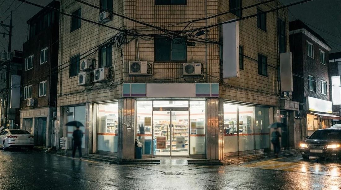 A convenience store lit up on a night street corner in Seoul