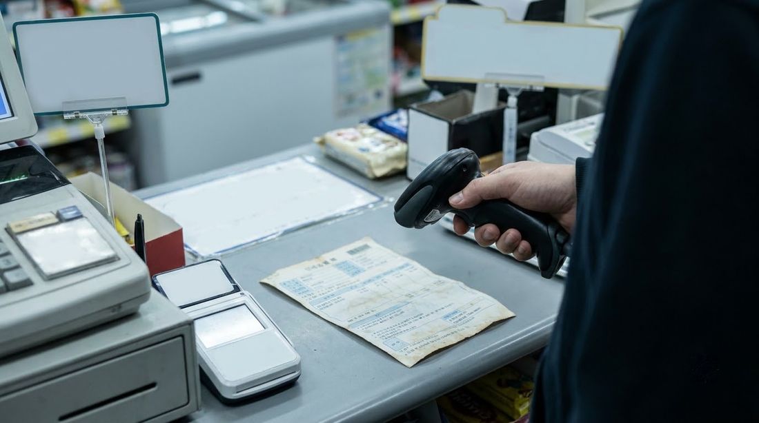 A barcode scanner reading a paper utility bill at a convenience store counter