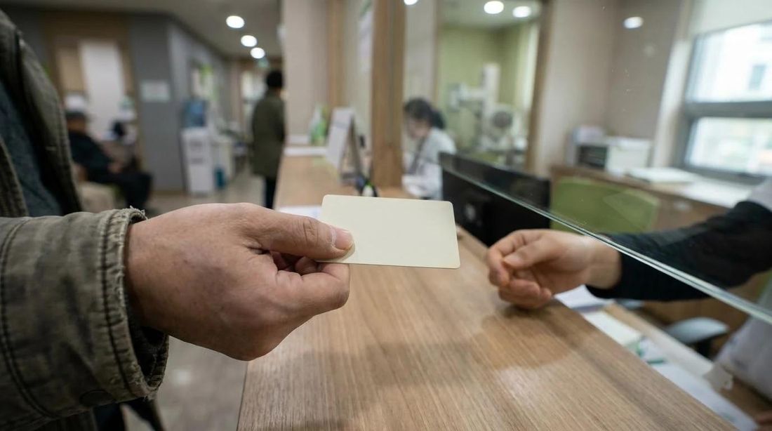 A hand passing a card across a clinic reception counter