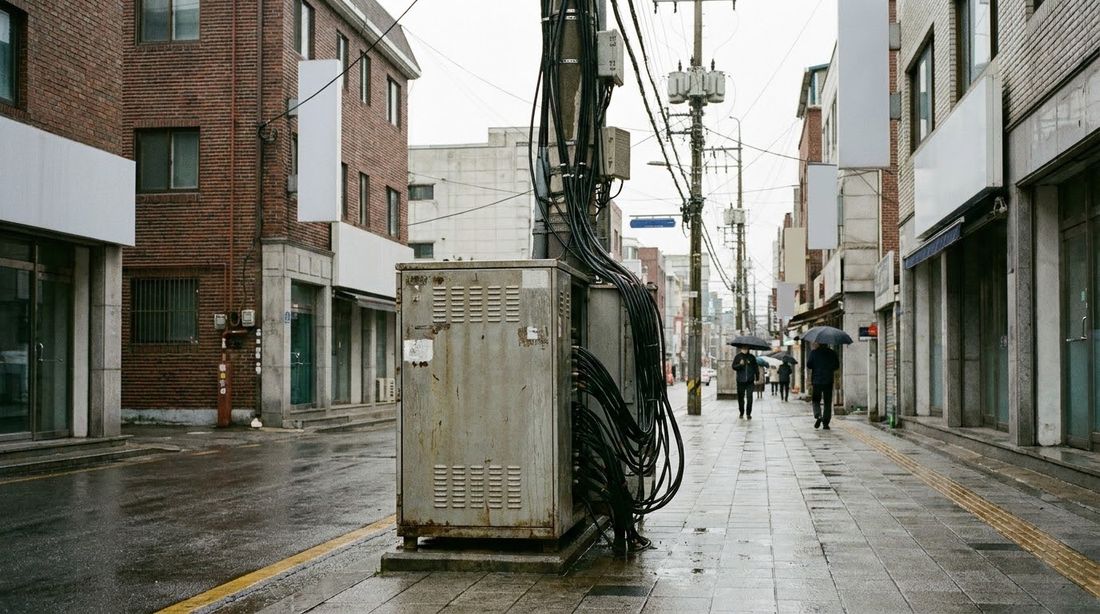 A street-side telecom equipment cabinet with cables running up a utility pole in Seoul