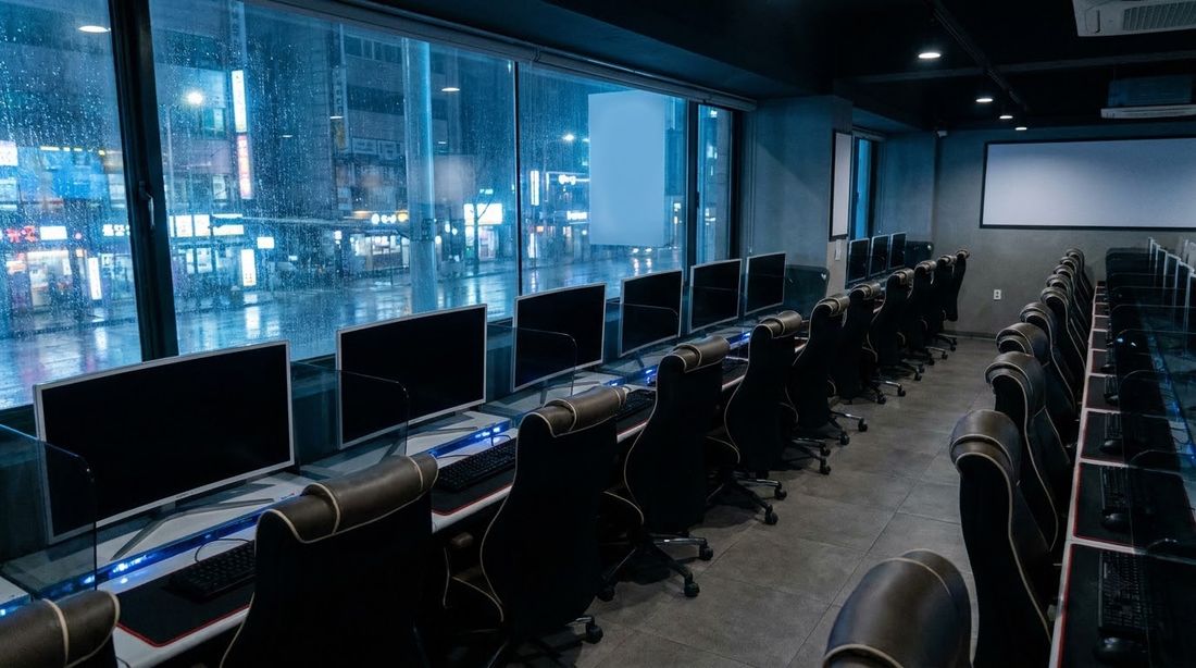 The interior of a Korean internet cafe at night with rows of dark monitors