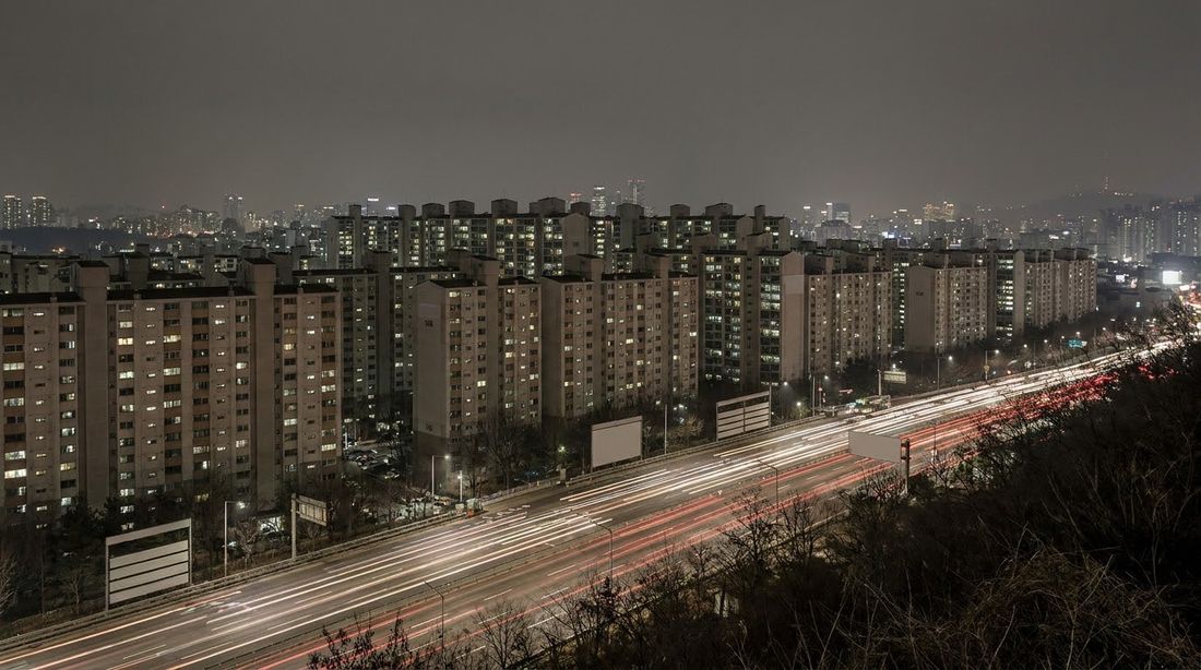A Korean apartment complex at night seen from a nearby hillside