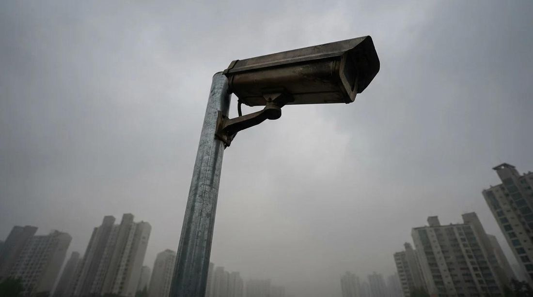 A surveillance camera on a pole against a grey sky