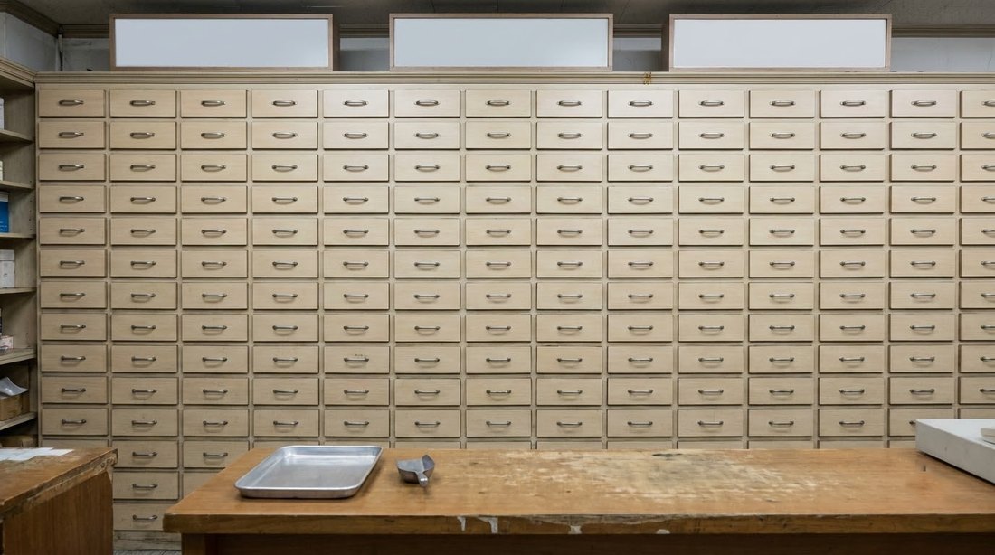 Rows of small medication drawers behind a Korean pharmacy counter