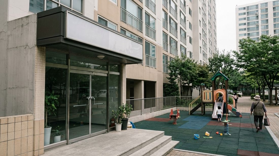 The ground-floor entrance to a shared community room in a Korean apartment tower, beside a children's playground
