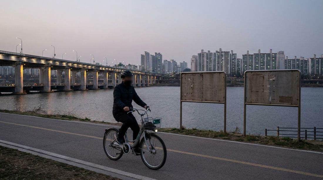 A cyclist riding a public rental bike along a riverside path in Seoul