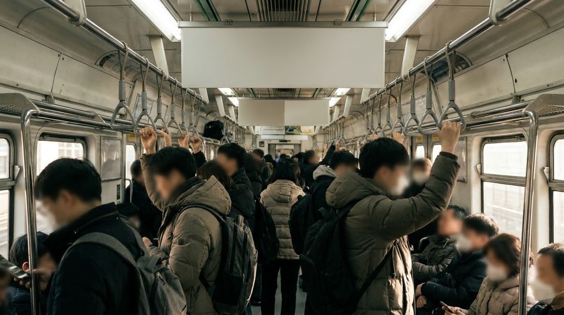 A crowded Seoul subway car with passengers holding overhead straps