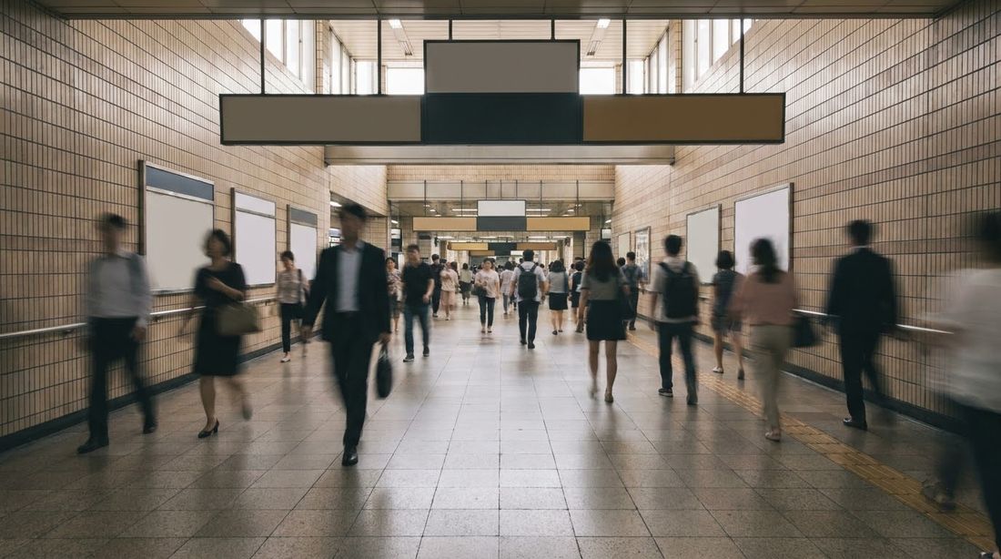 A transfer corridor in a Seoul subway station with commuters walking in both directions