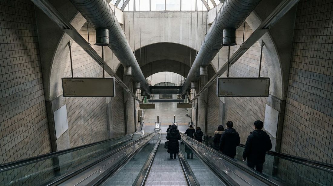 A long escalator descending into a deep Seoul subway station