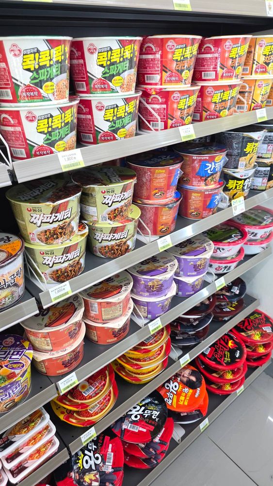 Four shelves of instant noodle cups with Korean price tags