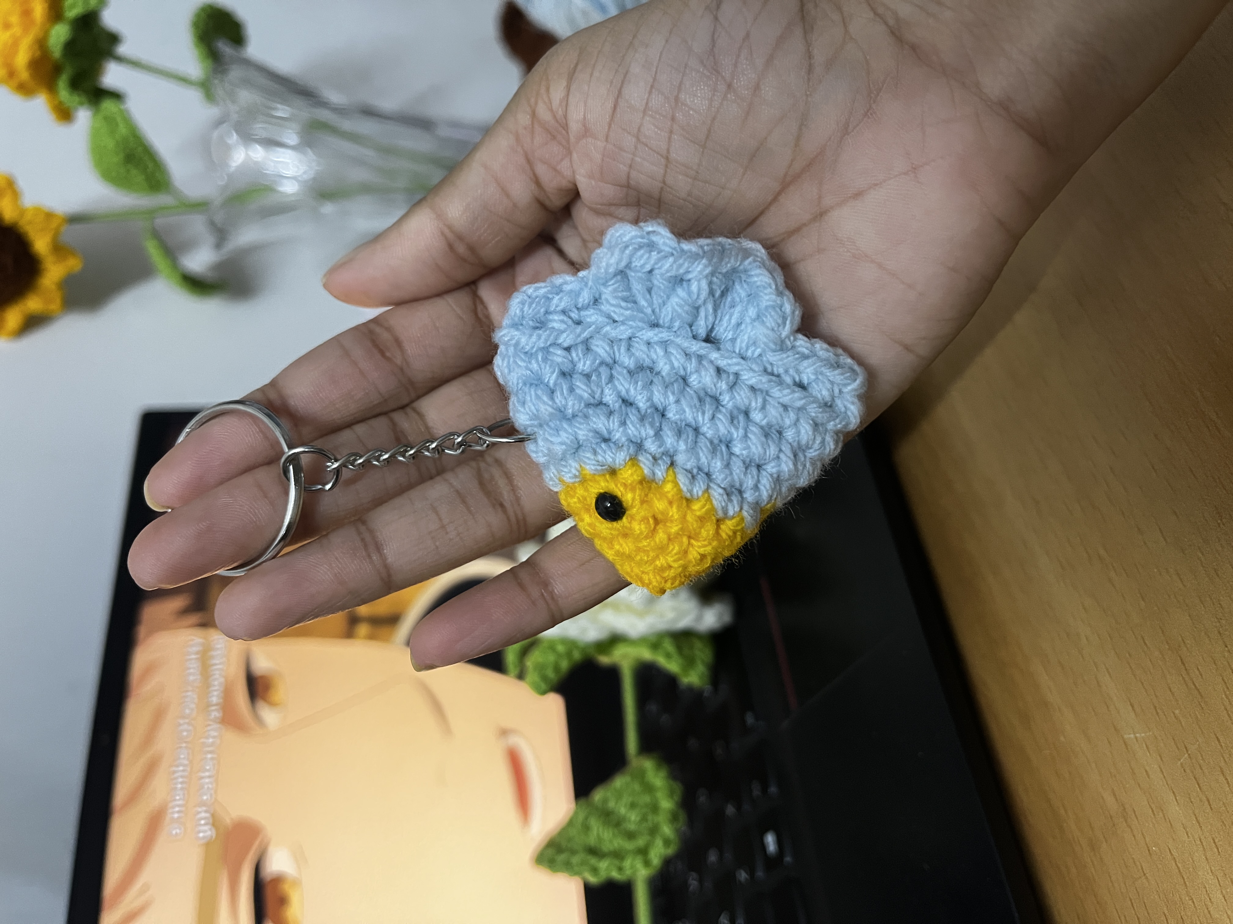 Crochet duck-in-a-cloud keychain charm held in palm of hand
