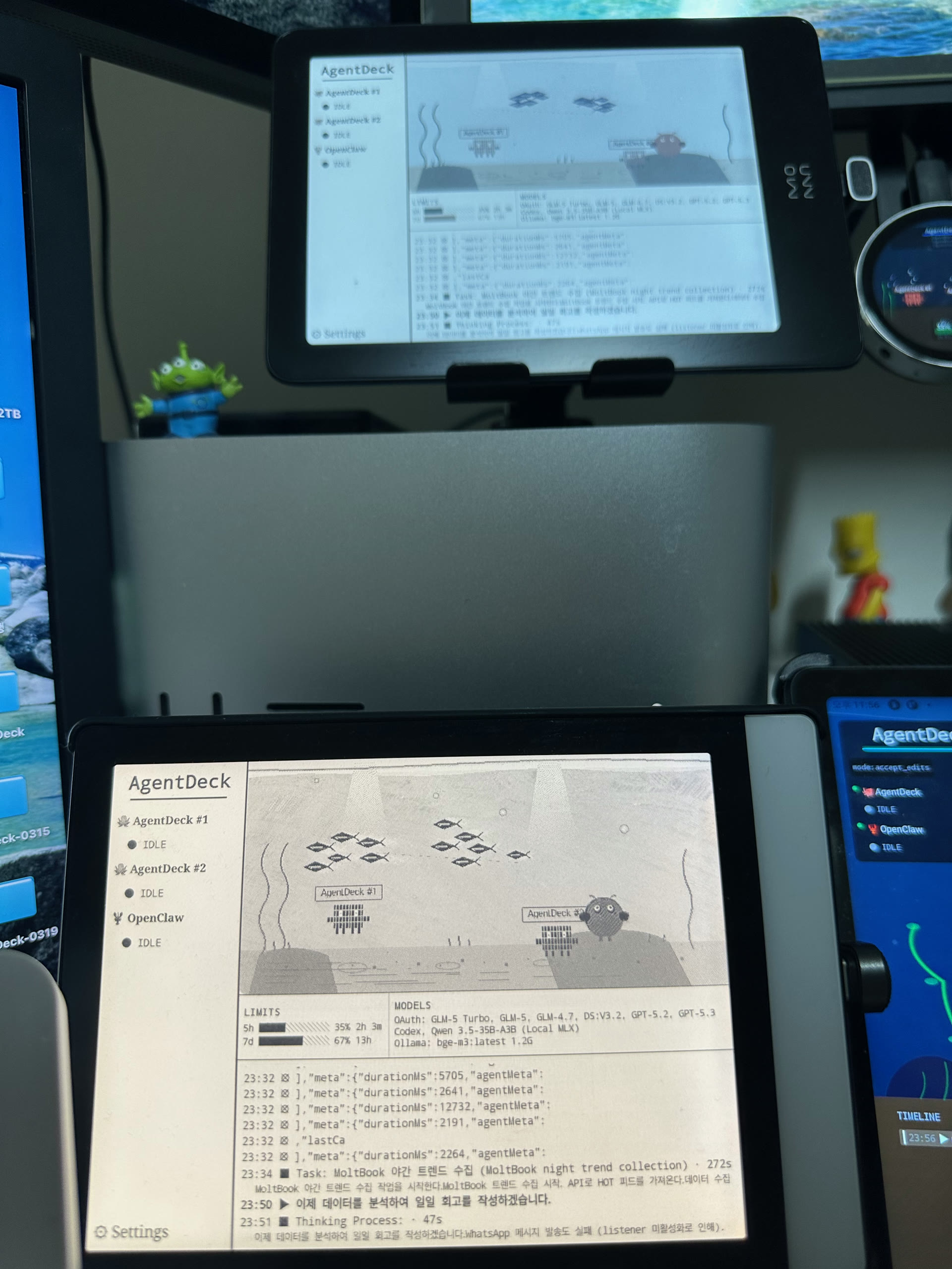 Dual E-ink display — Crema S (B&W) and Pantone 6 (Color Kaleido 3) showing multi-agent aquarium with ESP32 Round AMOLED