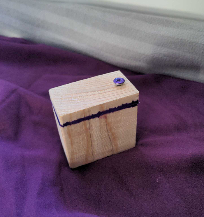 image of a small wooden box with a screw on top and a division one eigth of the way down form the top