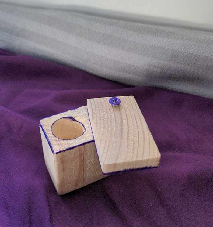 image of a small wooden box with a lid slightly ajar revealing an embedded circular hole.
