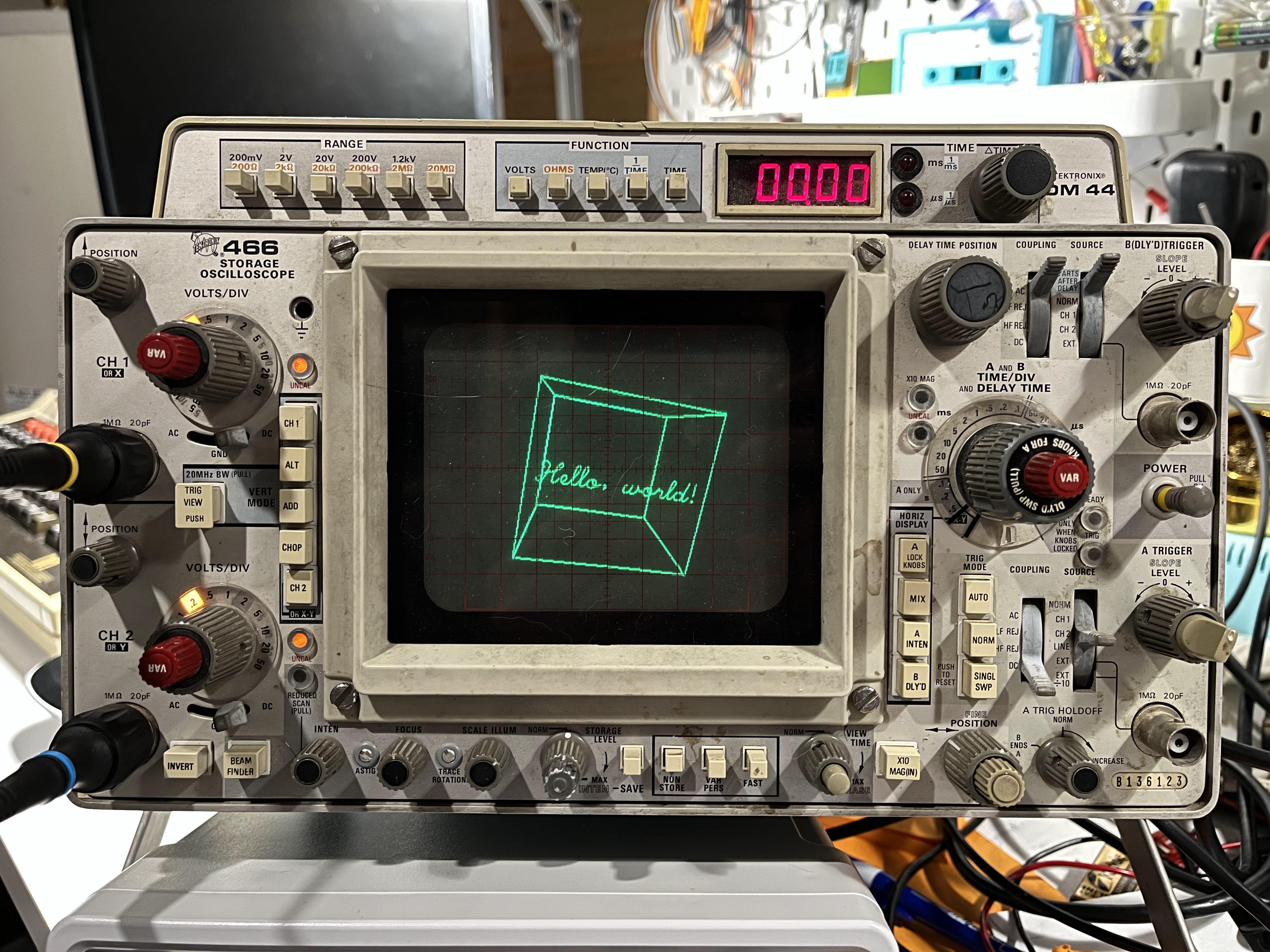 "Hello World" in cursive text inside a wireframe cube, displayed on a Tektronix 466 oscilloscope