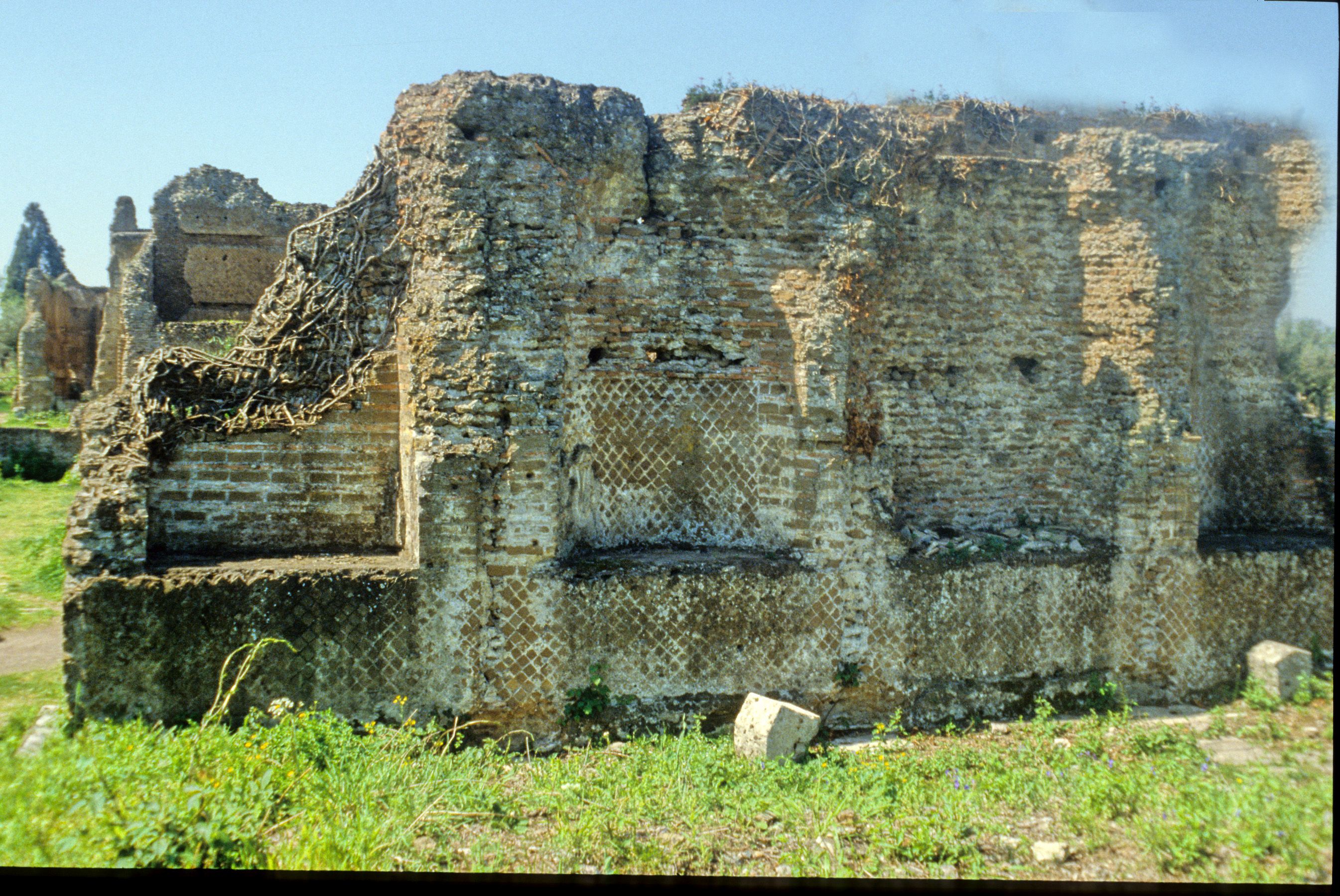 Photograph of the high wall, decorated by a series of alternating semicircular and square niches, which once enclosed the peristyle-garden on the eastern side of the Republican villa at Hadrian's Villa