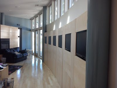 Photo showing six monitors surrounded by maple wood paneling along a curved wall.