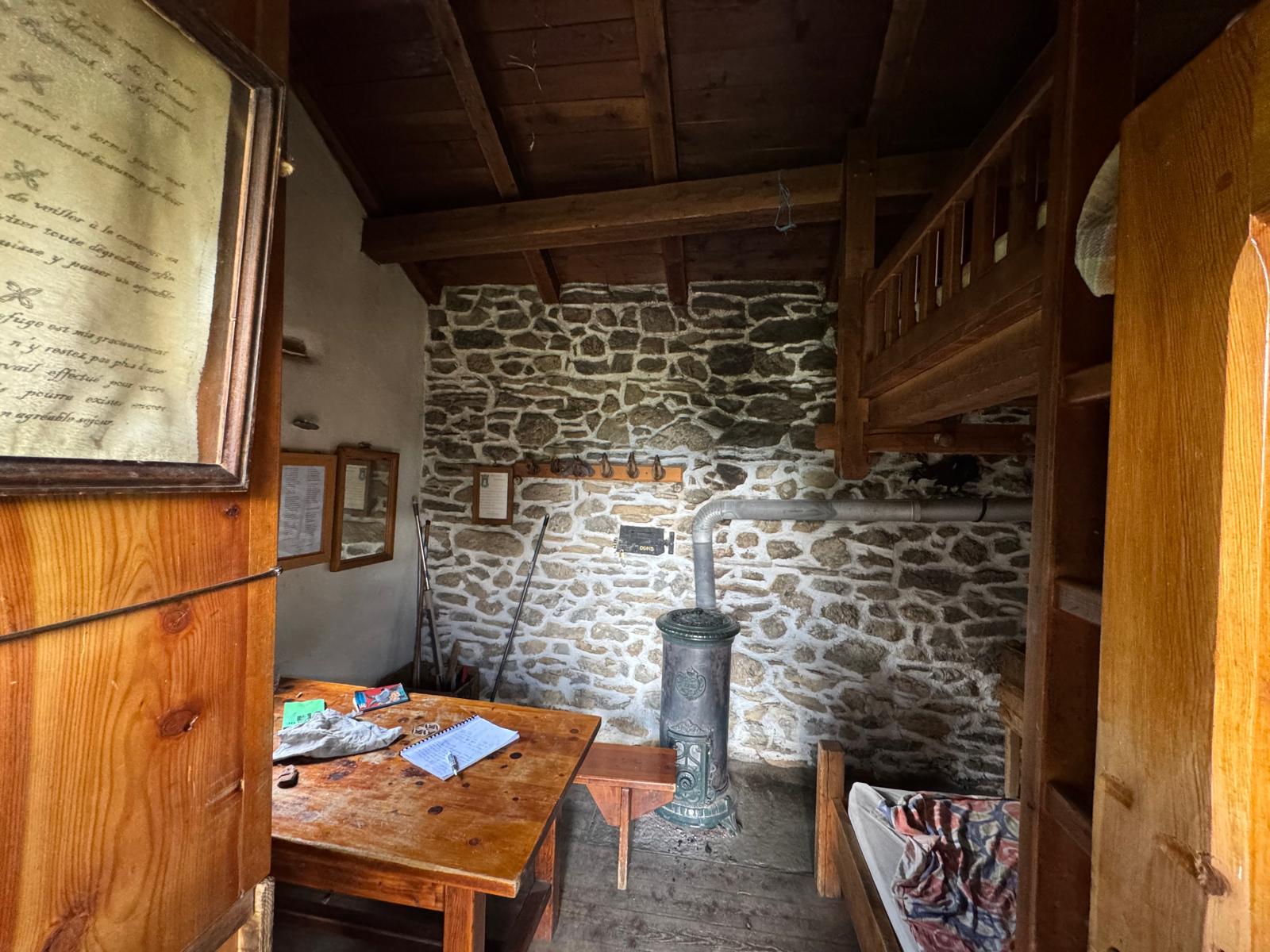 Intérieur de la cabane du Clot l'Henry : poêle, couchages et murs en pierre