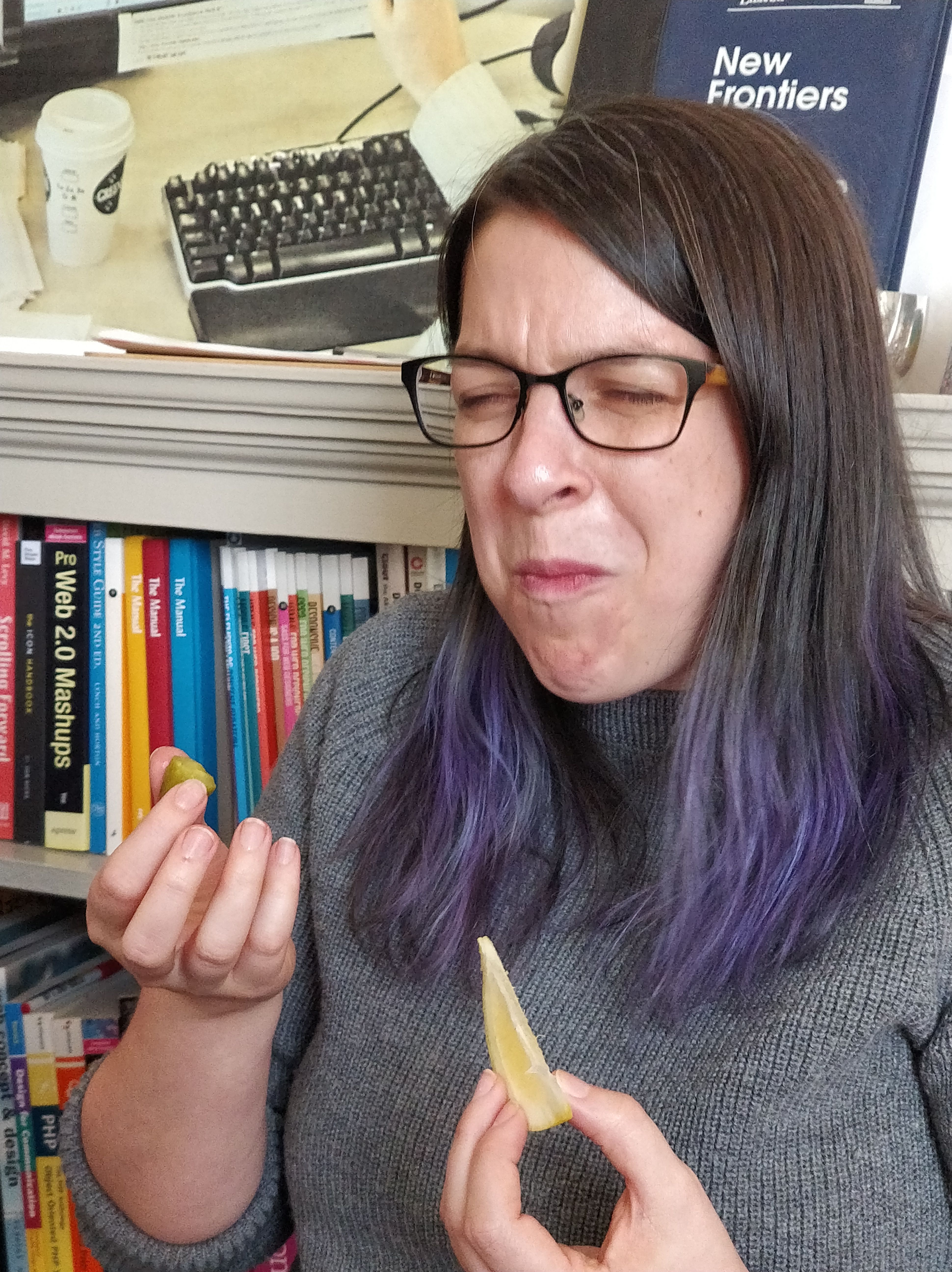 A person making a "this is sour" face while holding a lemon wedge