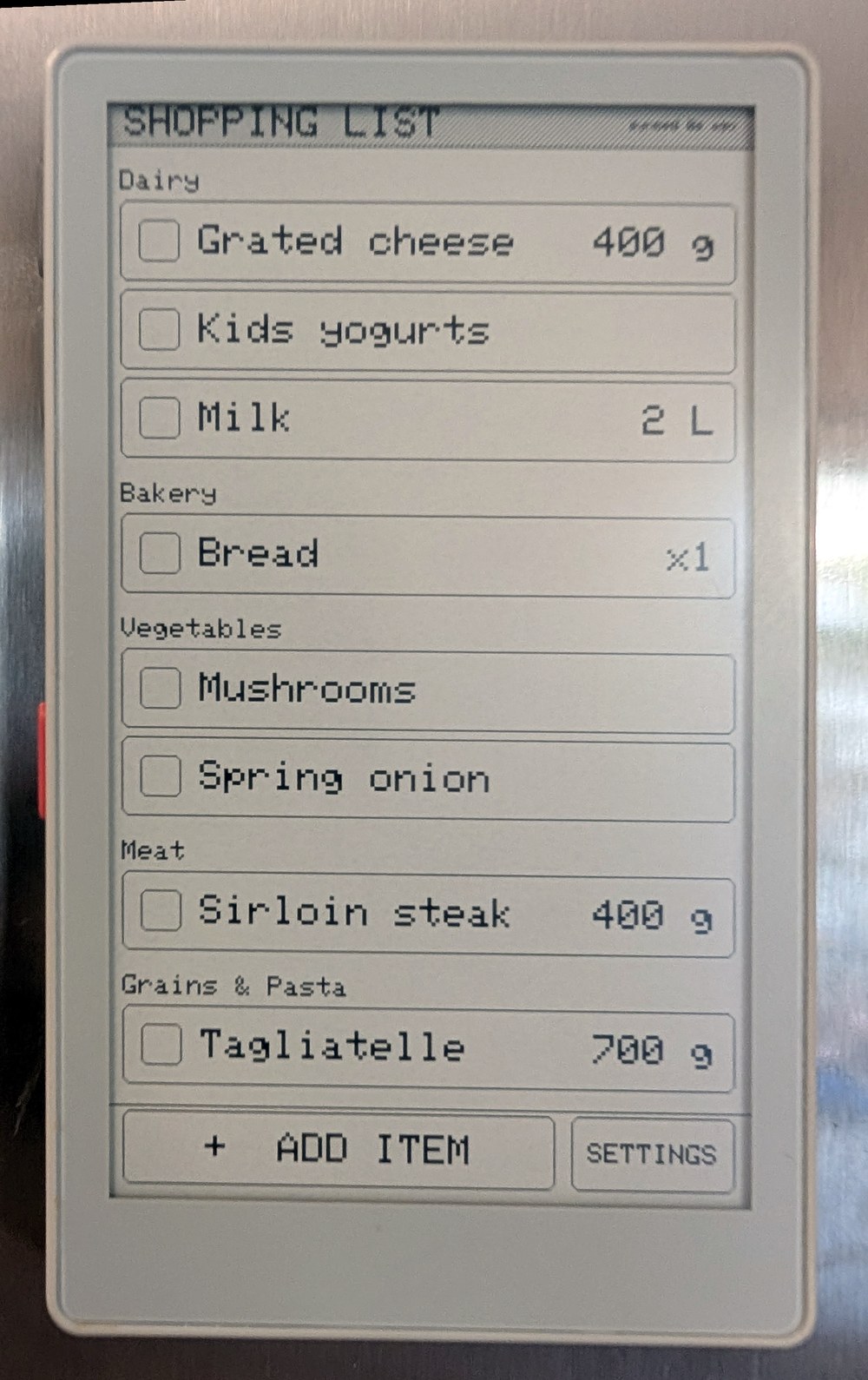 The PaperMono on a fridge, showing a shopping list grouped by aisle