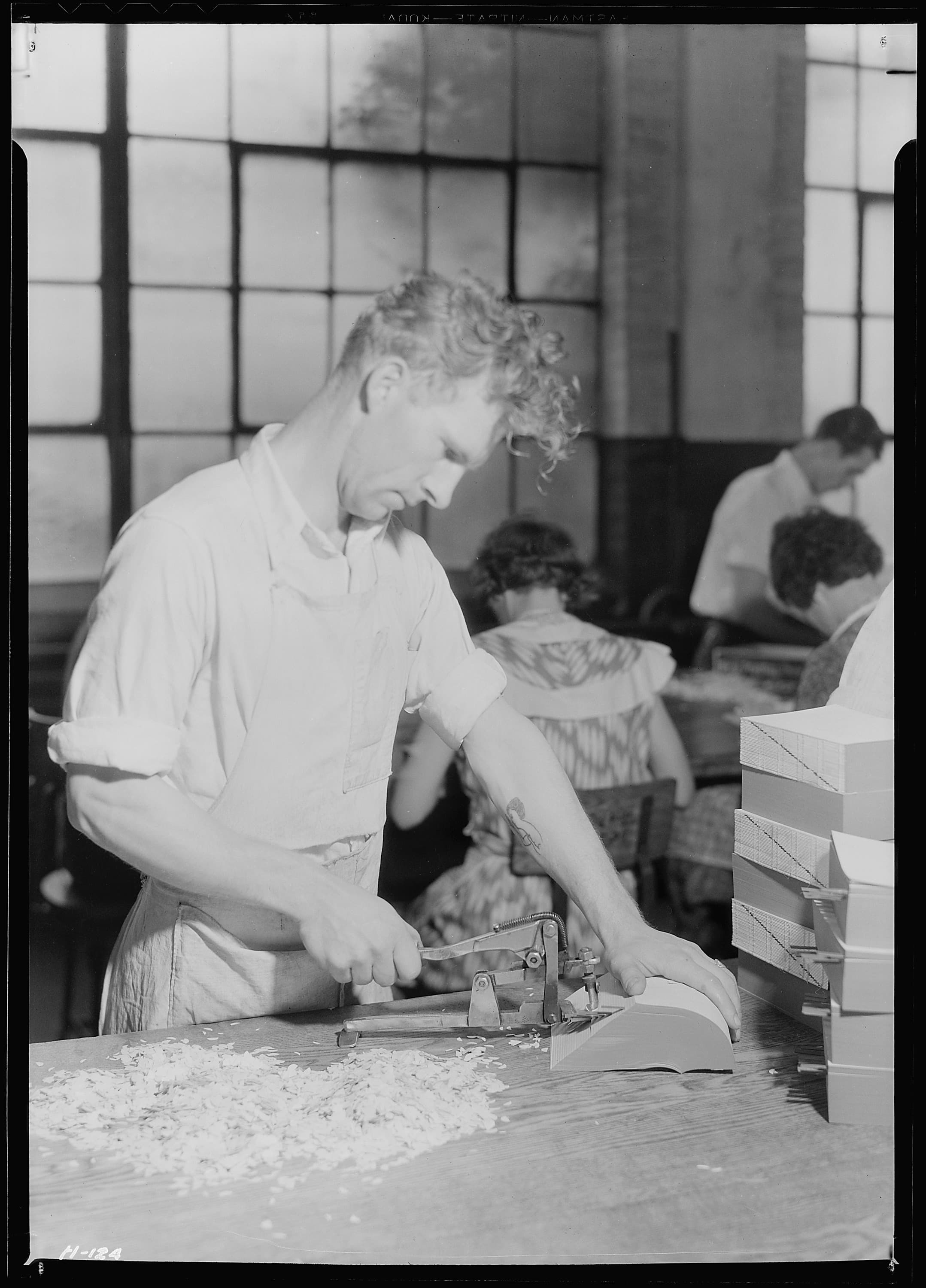 Washington, D.C. A worker in the Bureau of Engraving and Printing operating a machine which rounds the corners of the cards on which war savings stamps are mounted by John Vachon (1942)