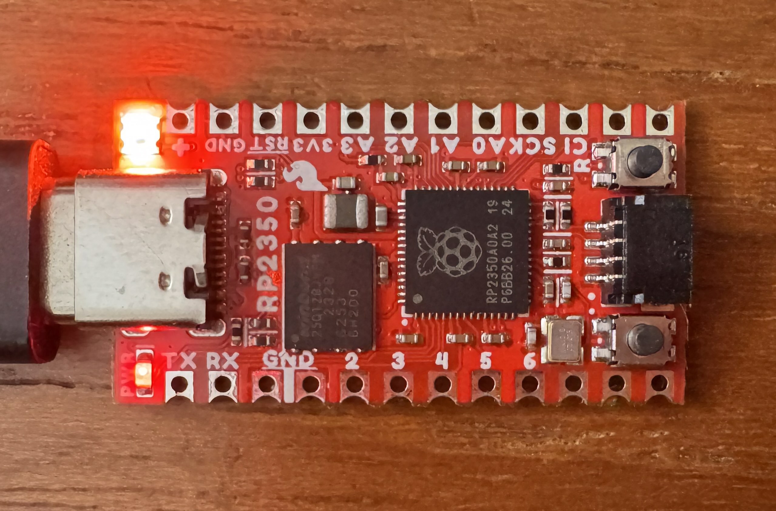 A SparkFun Pro Micro RP2350 board with its RGB LED glowing red.