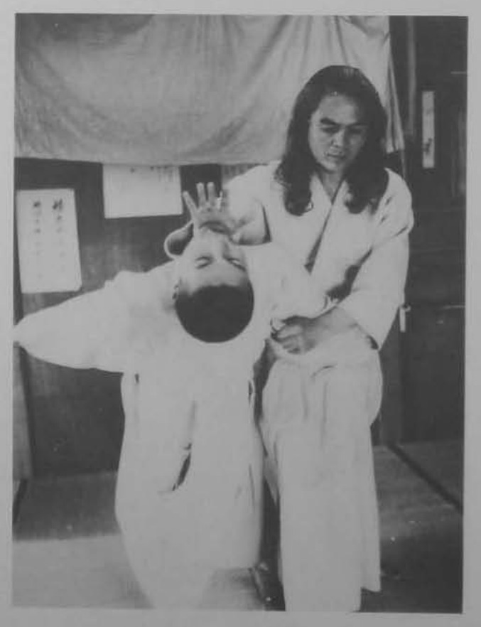 Dùng cùi chỏ phải đè hạ cổ đối phương.