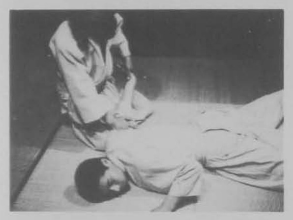 Đối phương nằm trên thảm, người thực hiện quỳ bên cạnh khóa giữ.