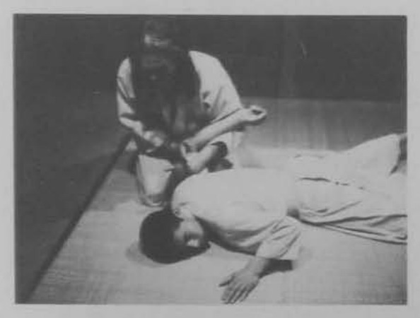 Đối phương nằm ngửa, người thực hiện quỳ giữ cánh tay.