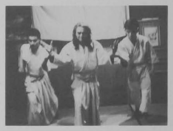 Võ sư dang hai tay khống chế hai môn sinh đang cúi người.