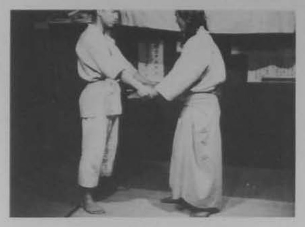 Hai người đứng, khống chế tay đối phương.
