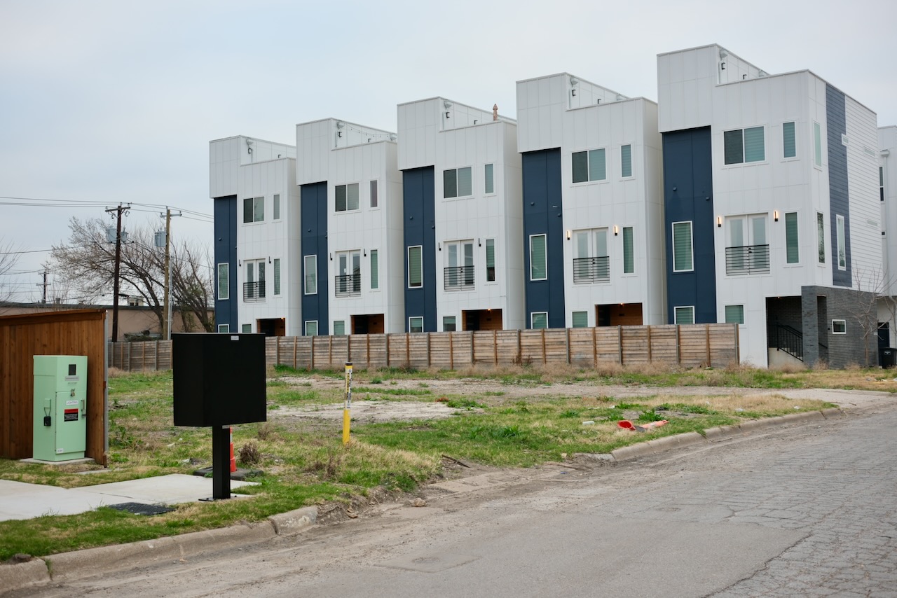 An empty, haggard field behind a brand new build