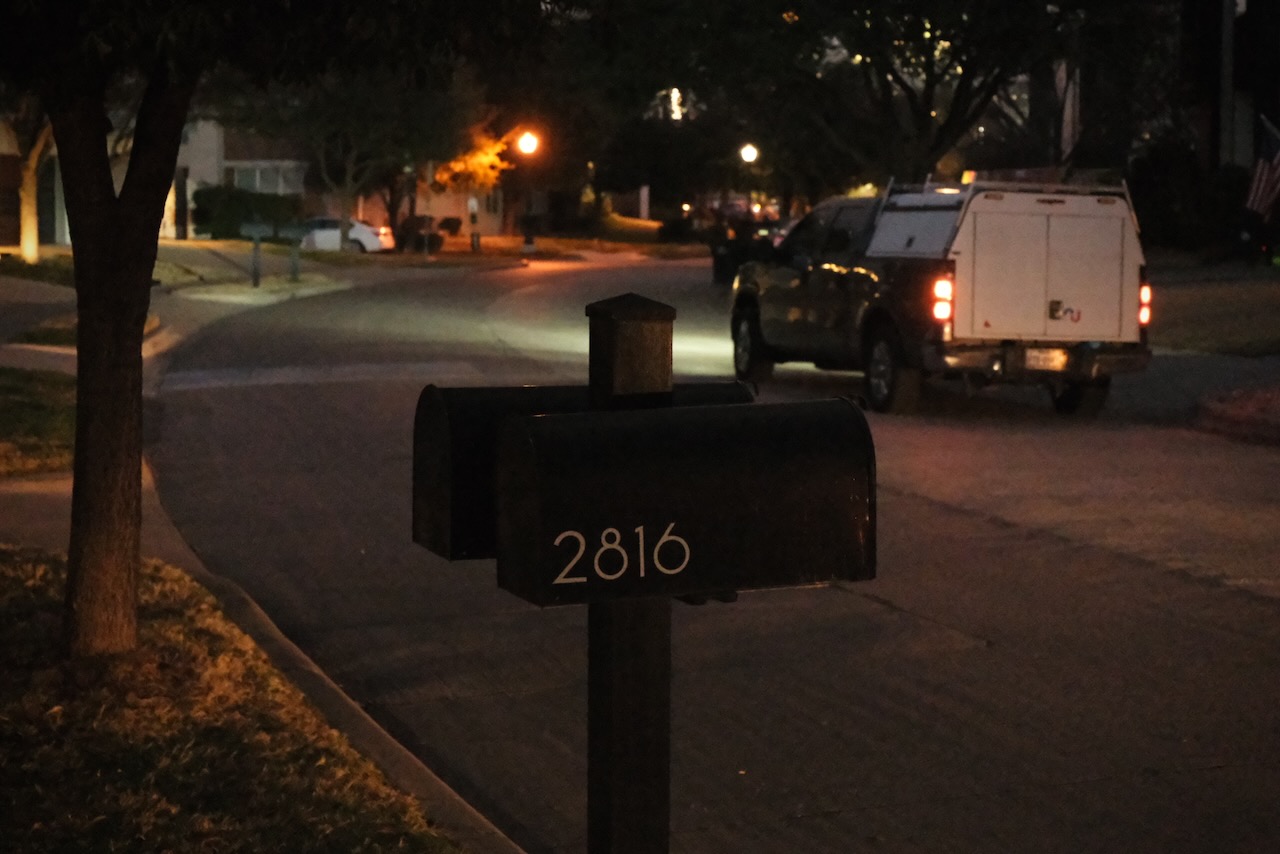 A winding street at night with new builds and a typical typeface on a mailbox