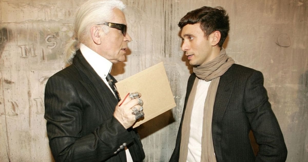 黒い服を着てインタビューに答えるファッションデザイナーの様子