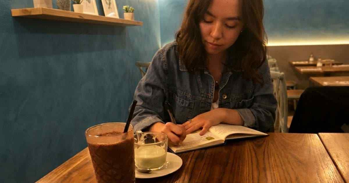 カフェでノートに書く女性