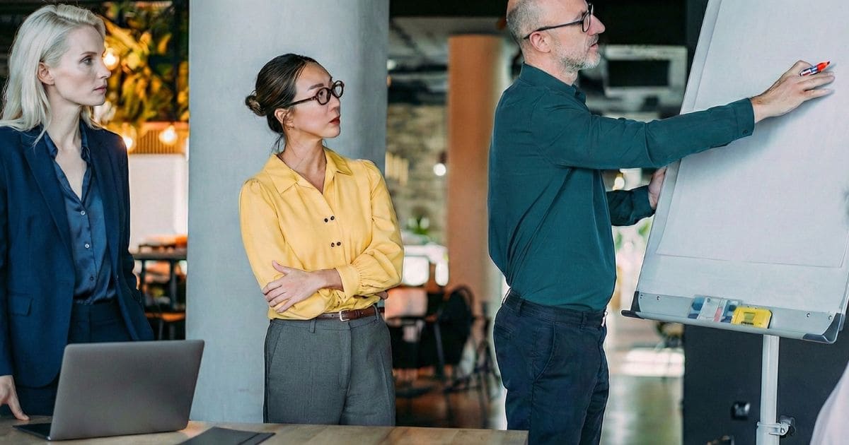 同僚と対話しながらホワイトボードに強みを書き出すビジネスパーソンの様子 同僚と対話しながらホワイトボードに強みを書き出すビジネスパーソンの様子