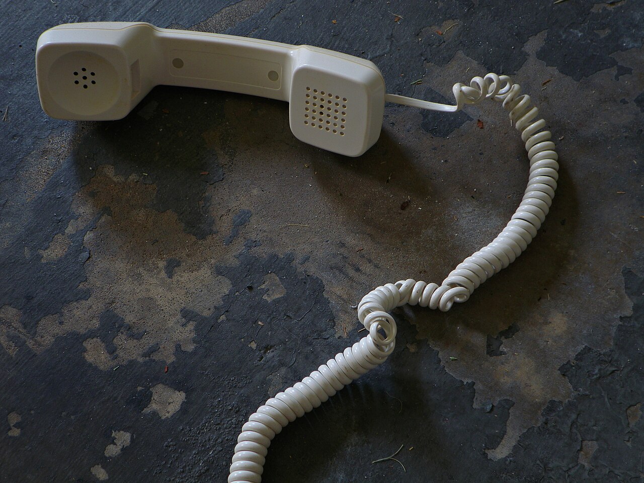 A coiled telephone handset cord lying on a floor, with two kinked loops where the spiral's handedness reverses