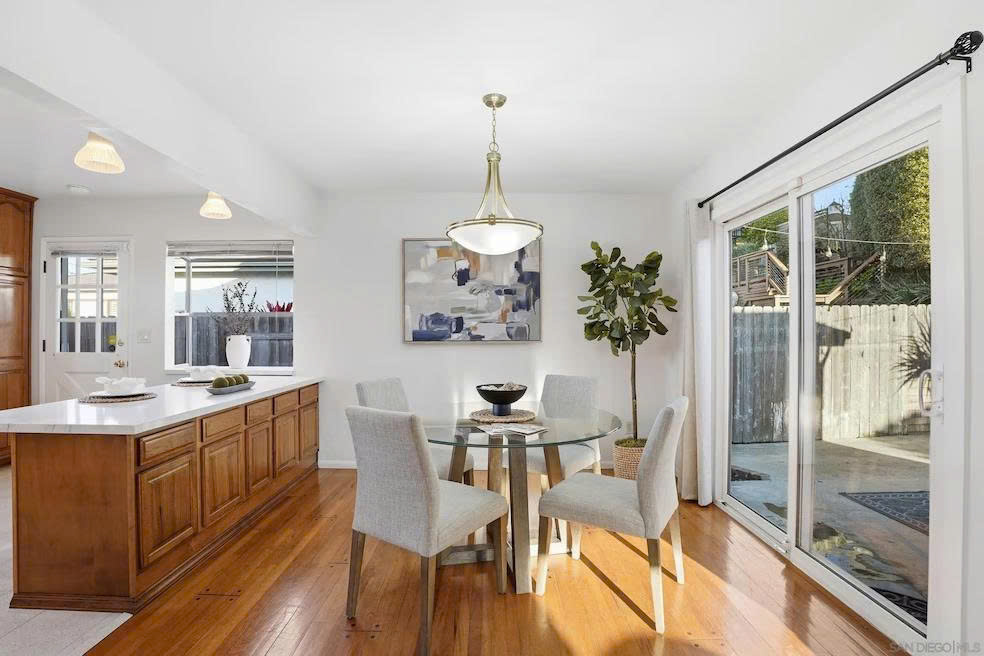 Dining area with glass table, kitchen island, and sliding glass door to backyard