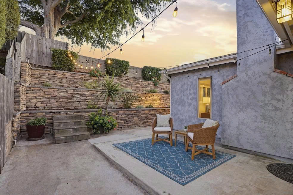 Cozy outdoor patio with string lights, stone wall, and seating area at dusk