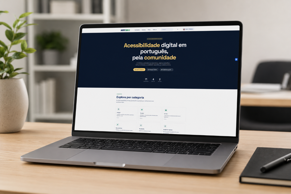 Notebook moderno sobre uma mesa de madeira em um escritório minimalista. Na tela, aparece a página inicial do site A11YBR, com destaque para o texto “Acessibilidade digital em português, pela comunidade”. Ao redor há uma planta, um caderno e uma caneta, com fundo desfocado.