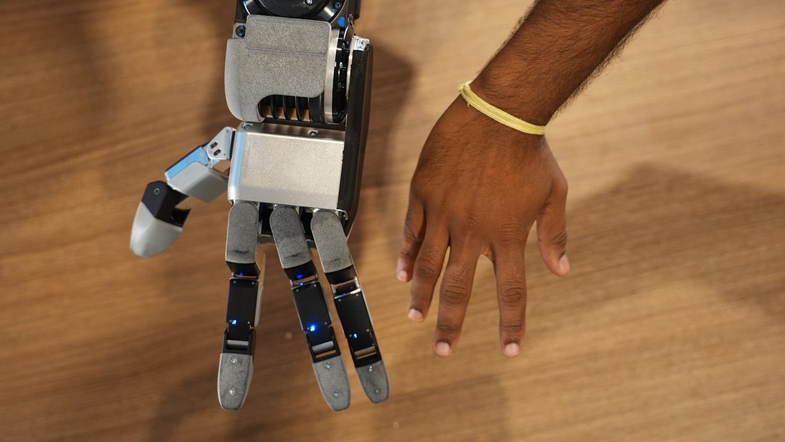 Atlas GR3 hand beside a human hand on a wooden table
