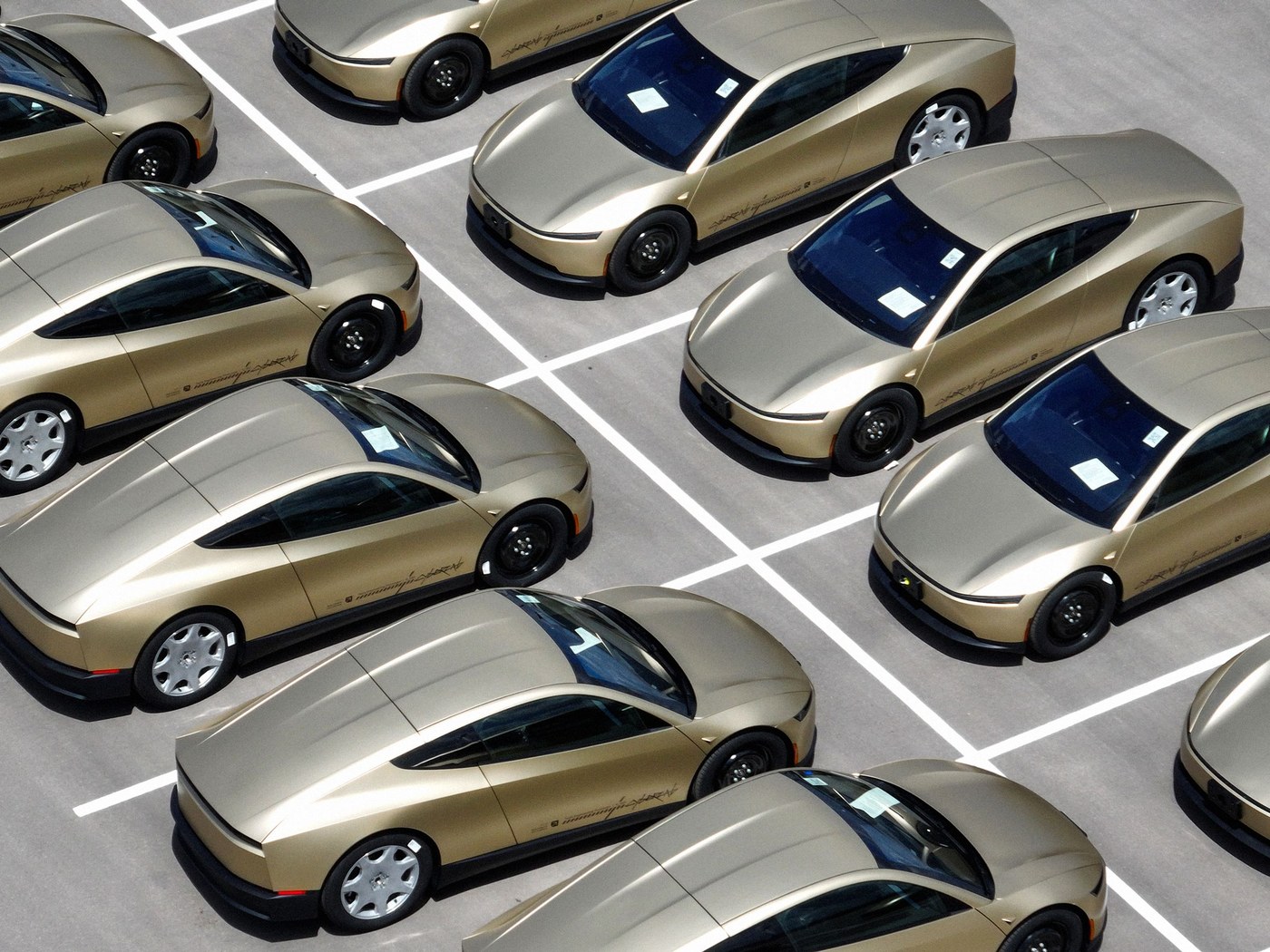 Aerial view of rows of gold Tesla Cybercabs lined up in a parking lot at Gigafactory Texas