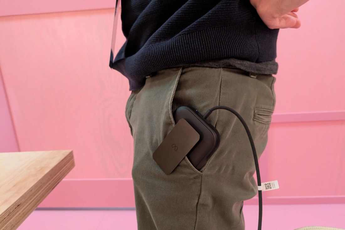 The compute puck sitting in a pants pocket with the tether cable looping down the leg