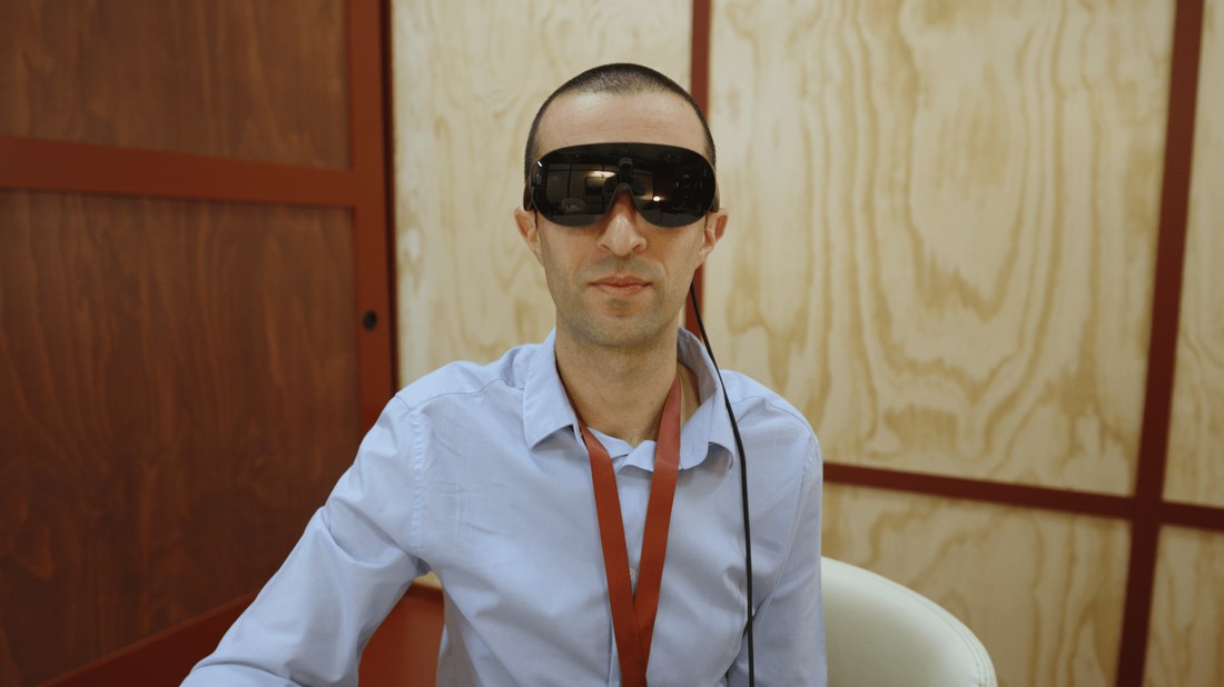 A reporter wearing the Meta VR Glasses at a Meta Connect demo booth, with the tether cable running down from the glasses