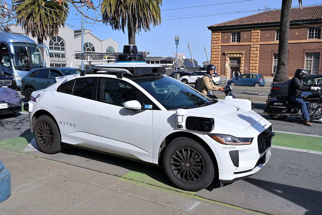 White Waymo Jaguar I-PACE with roof lidar pod driving in San Francisco