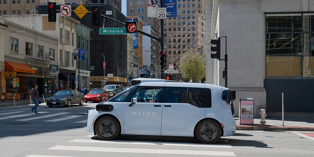 Waymo Zeekr-built Ojai robotaxi with WAYMO branding crossing an intersection in San Francisco
