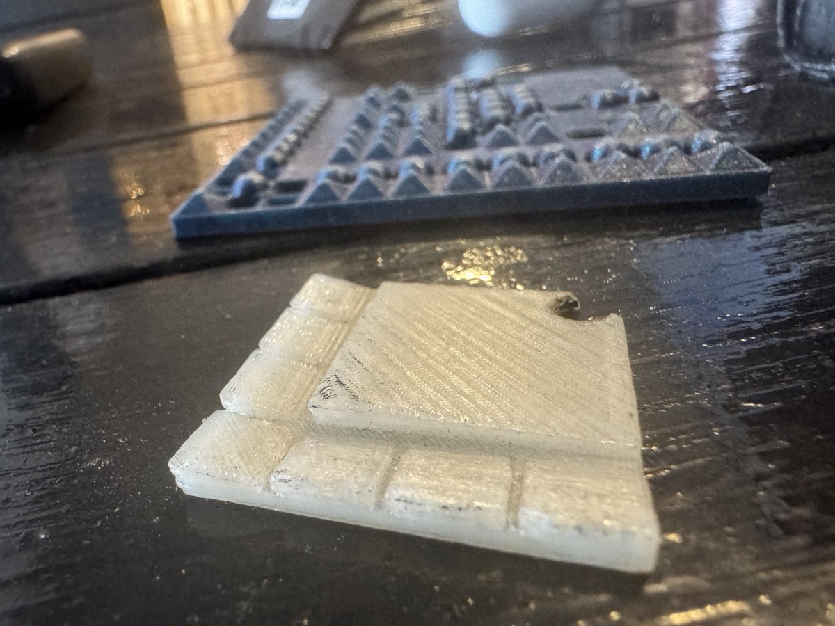 The keyring in front of the printed 12 by 12 grid: a flat slab with one row of small blocks and one column of small blocks along two of its edges
