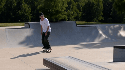 A skateboarder pops an ollie, spins 180 degrees and rolls away backwards