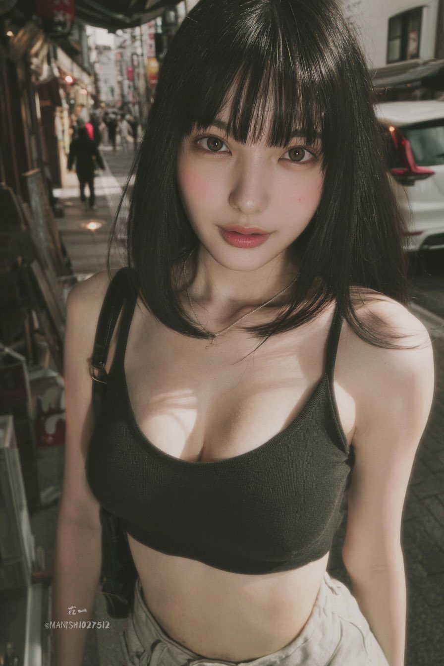 A candid snapshot of a young woman with straight black hair, blunt bangs, large expressive eyes, and fair skin, stand…
